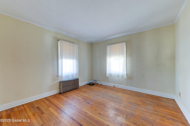 unfurnished room featuring hardwood / wood-style floors, radiator, baseboards, and ornamental molding