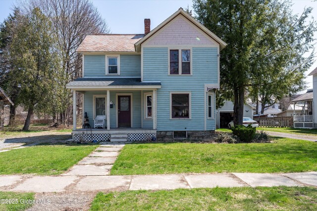 victorian-style house with a chimney, a front lawn, and a porch