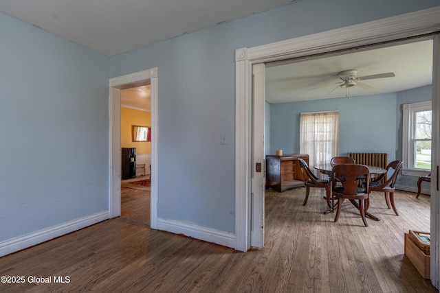 interior space featuring baseboards, a ceiling fan, and wood finished floors