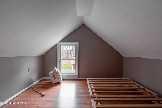 additional living space featuring vaulted ceiling and wood finished floors