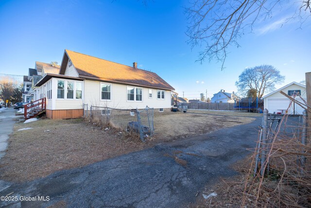 view of home's exterior with a chimney, a trampoline, and fence