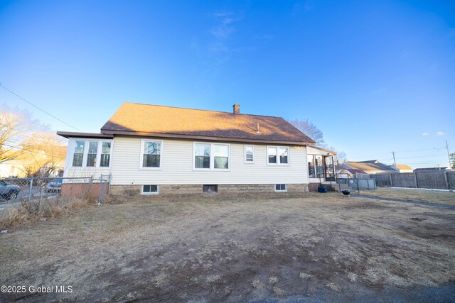 back of property with a chimney and fence