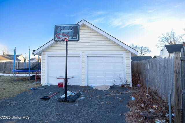 detached garage featuring a trampoline and fence