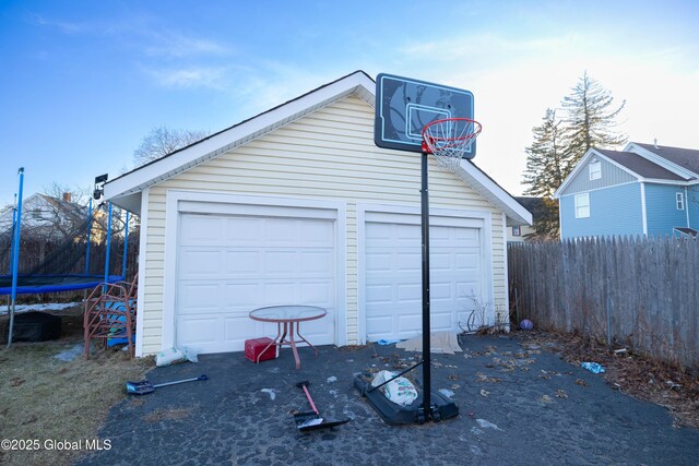 detached garage featuring a trampoline and fence