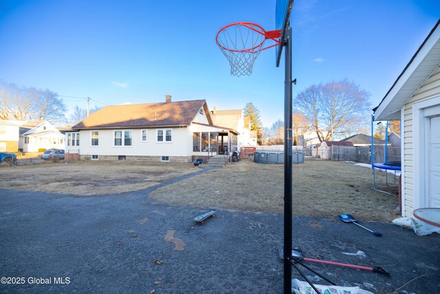 exterior space featuring a residential view, a trampoline, and fence