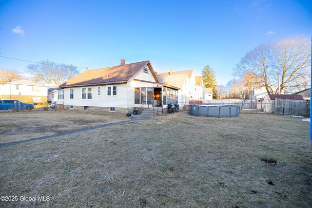 rear view of property featuring a fenced in pool, fence, and a chimney