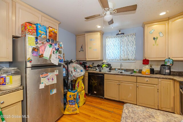 kitchen featuring light wood-style flooring, freestanding refrigerator, a sink, black dishwasher, and backsplash