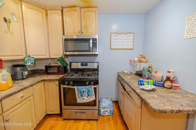 kitchen with appliances with stainless steel finishes, light wood-style flooring, and light brown cabinets