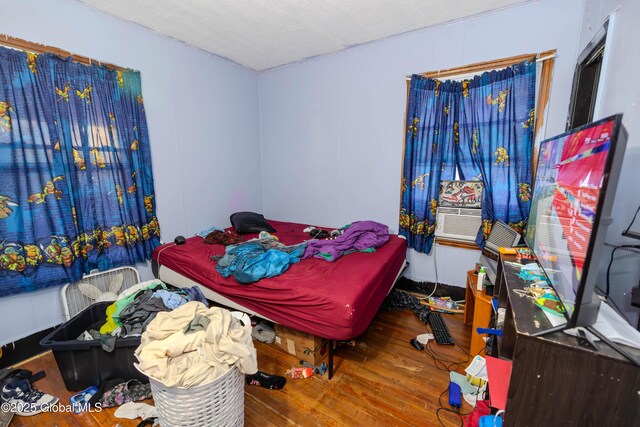 bedroom with cooling unit and wood finished floors