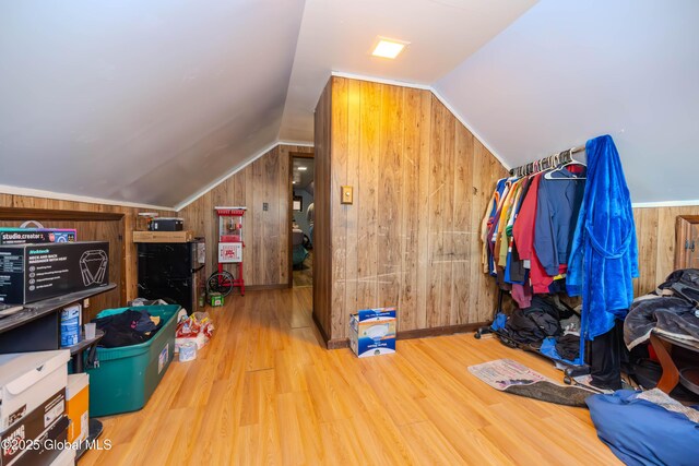 additional living space featuring wood walls, wood finished floors, and vaulted ceiling