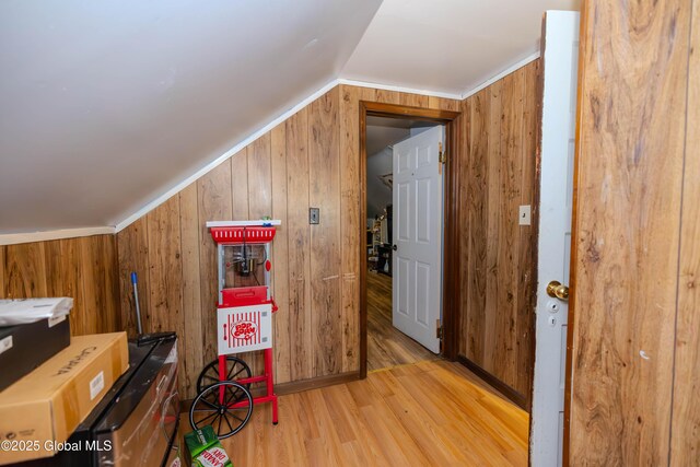 bonus room with wood walls, light wood-type flooring, and lofted ceiling