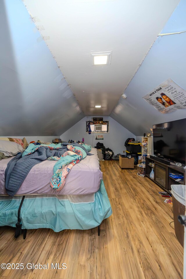 bedroom with wood finished floors and vaulted ceiling