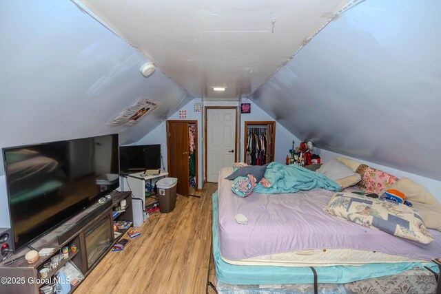 bedroom with a closet, lofted ceiling, and wood finished floors