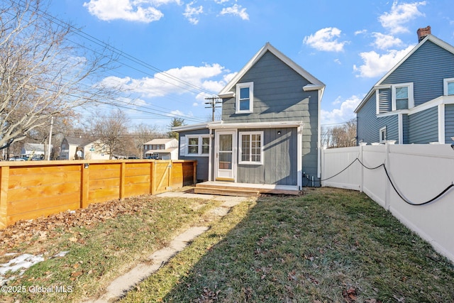 rear view of property featuring a yard and a fenced backyard