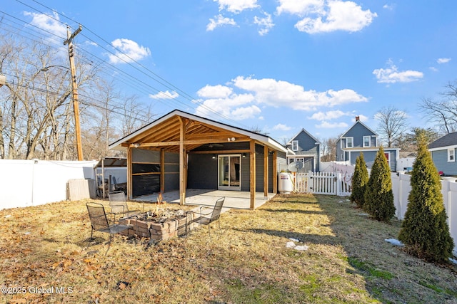 rear view of house with a gate, a patio area, a fenced backyard, and a fire pit