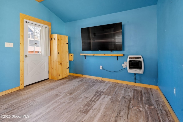 interior space featuring heating unit, baseboards, lofted ceiling, and wood finished floors