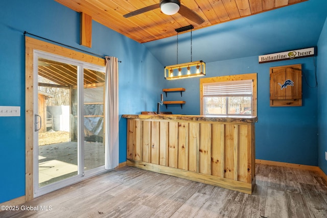 interior space with baseboards, lofted ceiling, wooden ceiling, wood finished floors, and a ceiling fan