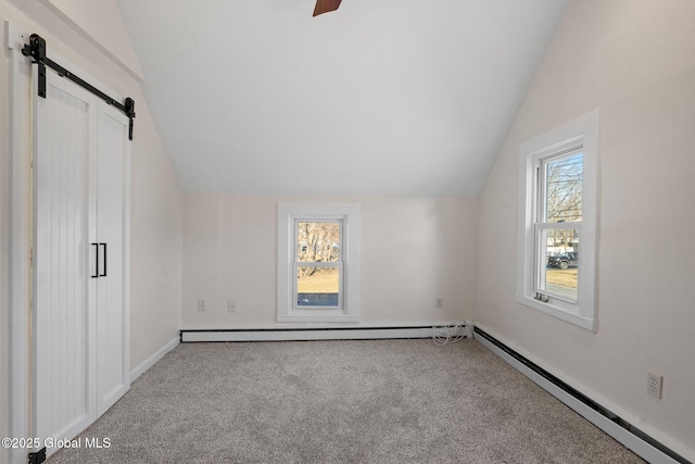 additional living space featuring baseboard heating, a healthy amount of sunlight, and a barn door