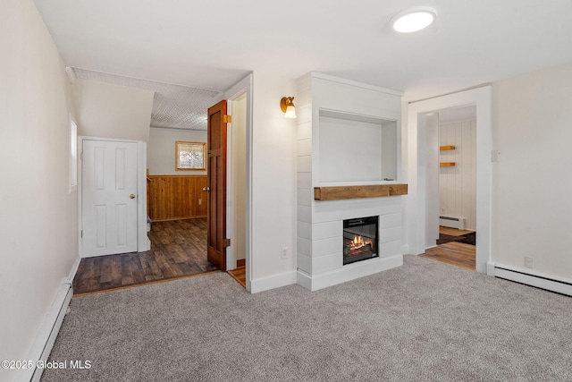 unfurnished living room with a baseboard heating unit, a glass covered fireplace, carpet floors, and a baseboard radiator