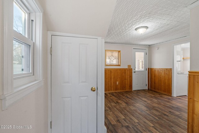 foyer entrance featuring a wainscoted wall, wood walls, a textured ceiling, and dark wood-style flooring