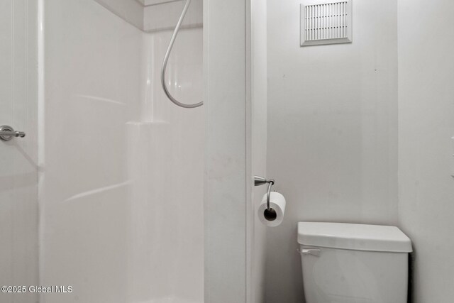 bathroom featuring visible vents, toilet, and a shower