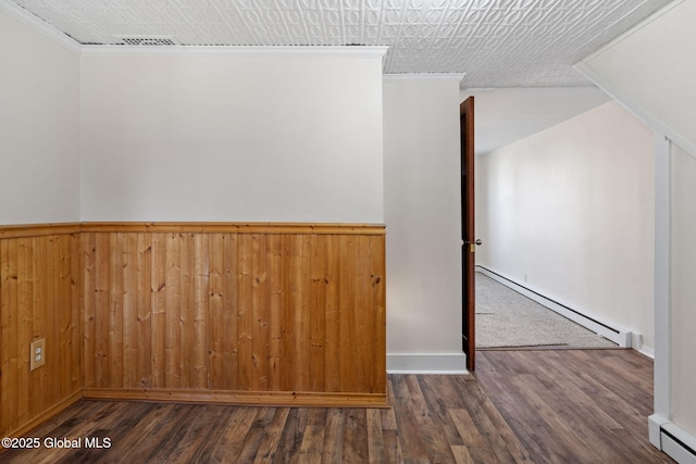 spare room with a baseboard radiator, wood finished floors, and crown molding