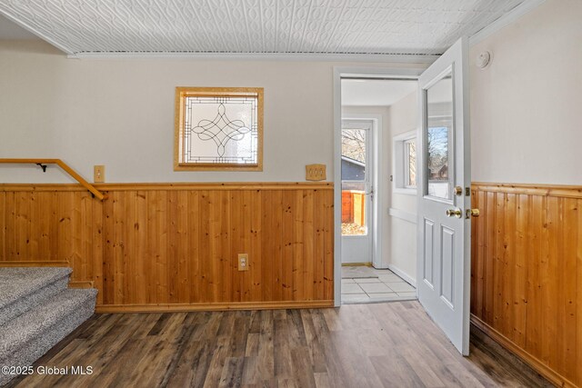 entryway with stairway, wood finished floors, a wainscoted wall, wood walls, and a textured ceiling