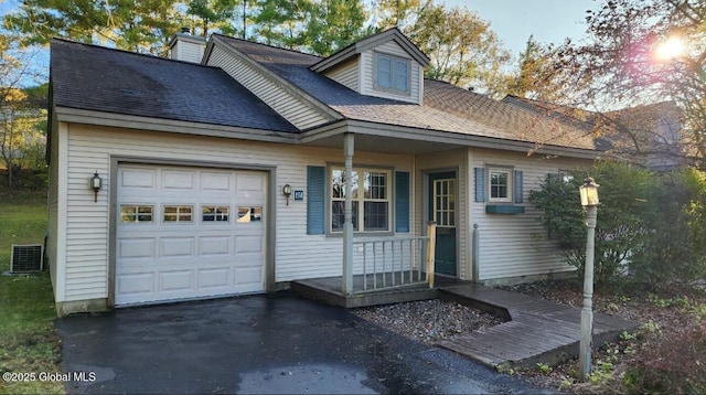 cape cod home with an attached garage, cooling unit, and roof with shingles