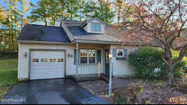 cape cod home with a shingled roof, aphalt driveway, a garage, and a chimney