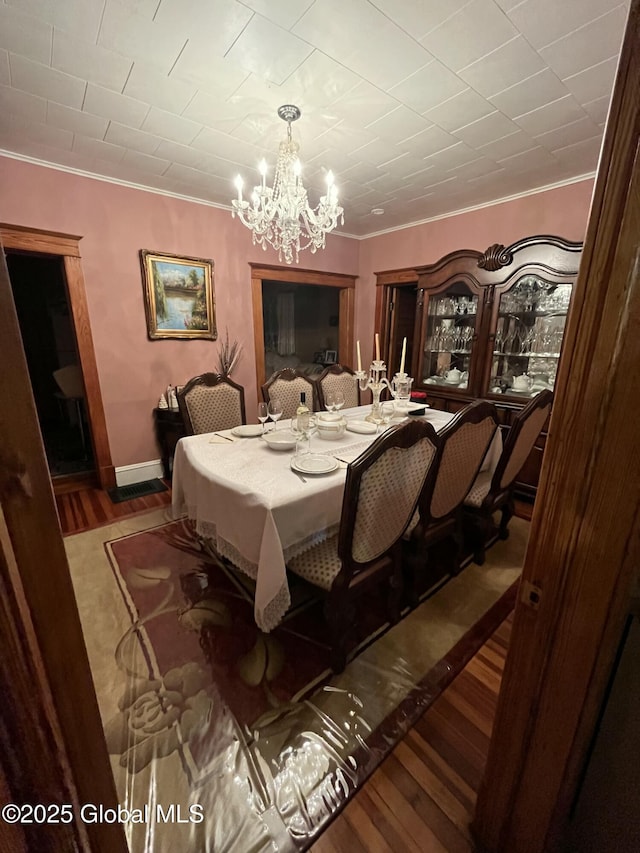 dining room with a notable chandelier, crown molding, baseboards, and wood finished floors