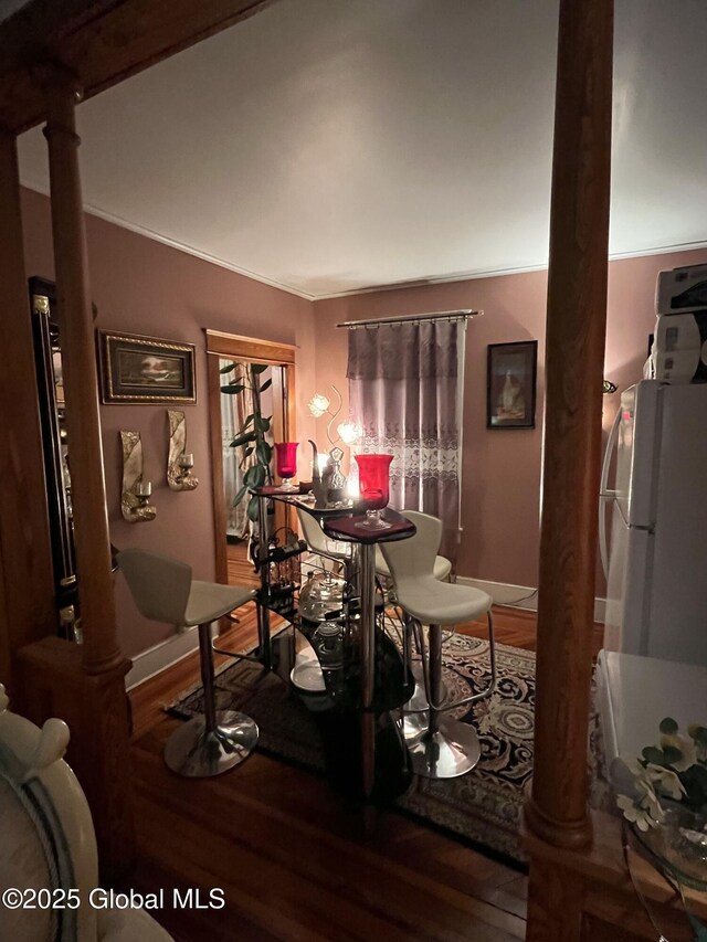 dining area with wood finished floors, baseboards, and ornate columns