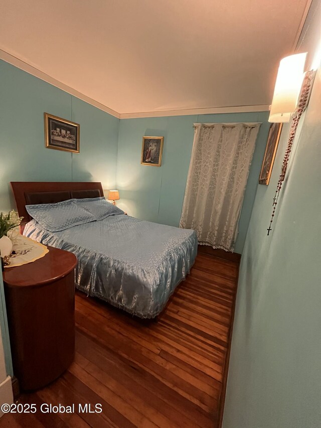bedroom with wood finished floors and ornamental molding