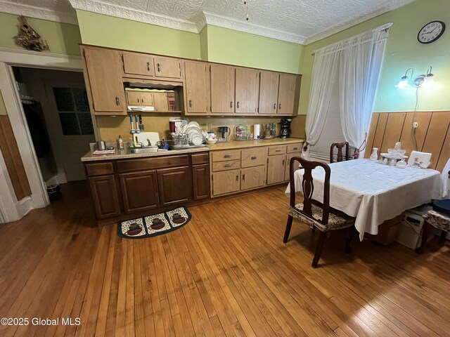 kitchen featuring light wood-style flooring, an ornate ceiling, light countertops, and a sink