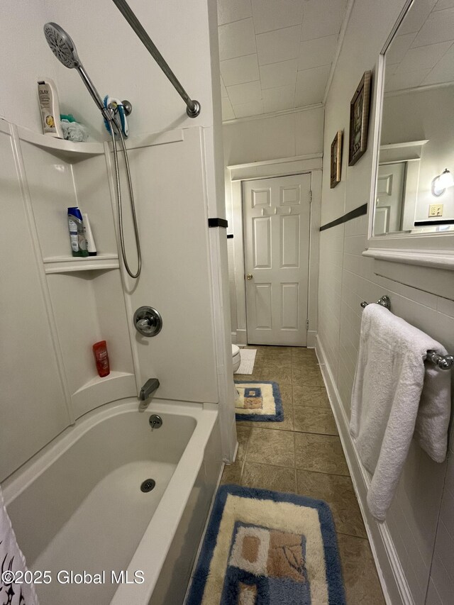 full bath featuring ornamental molding, bathing tub / shower combination, toilet, tile walls, and tile patterned floors