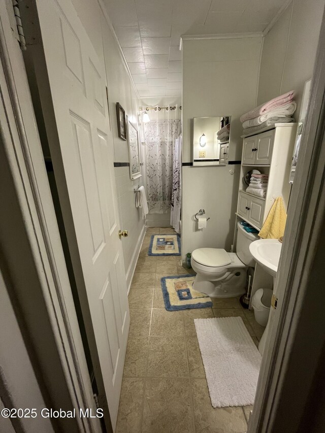 full bathroom with tile patterned floors, curtained shower, toilet, and crown molding