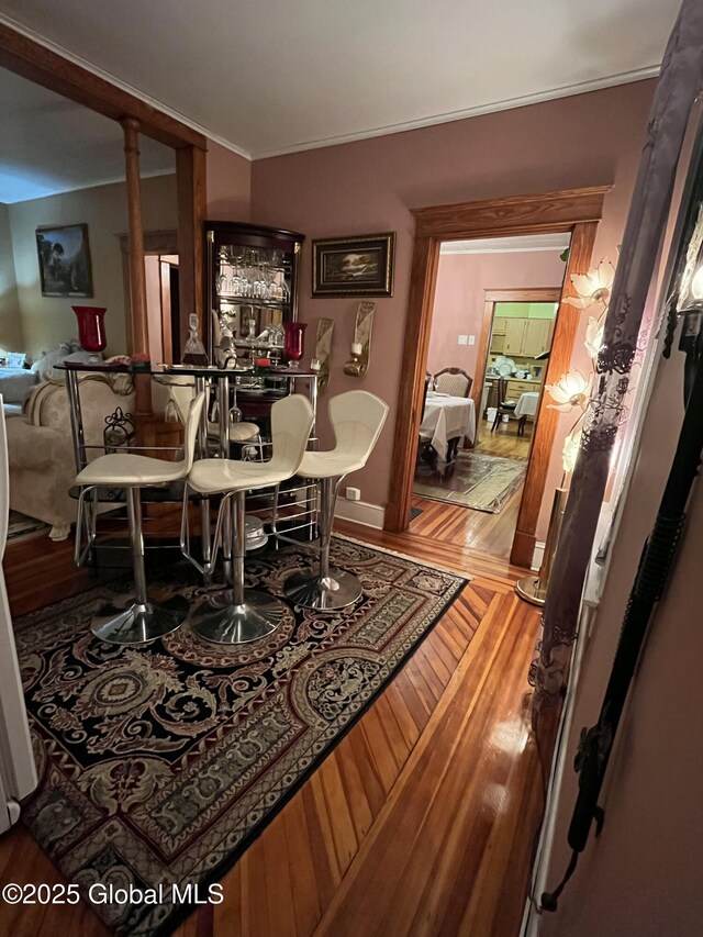 dining room with a bar, crown molding, and wood finished floors