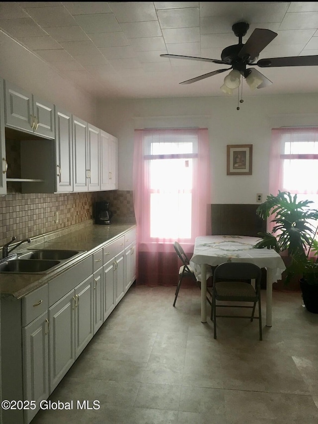 kitchen with a sink, backsplash, a healthy amount of sunlight, and white cabinetry