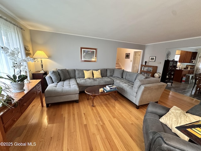 living room featuring stairs, light wood-style flooring, and crown molding