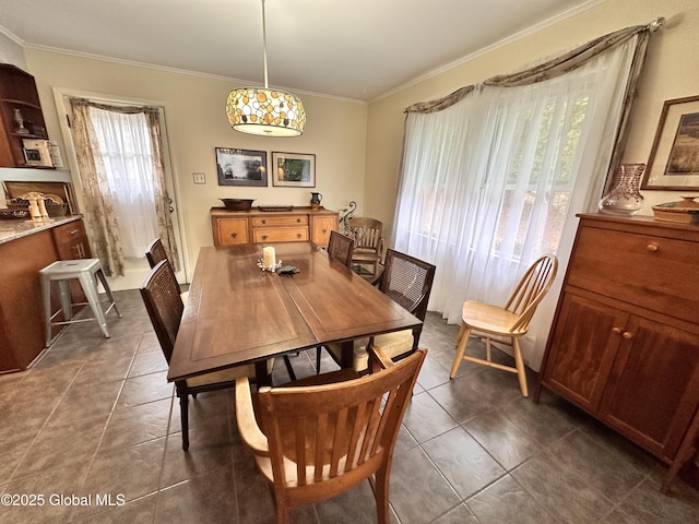 dining space featuring dark tile patterned flooring and crown molding