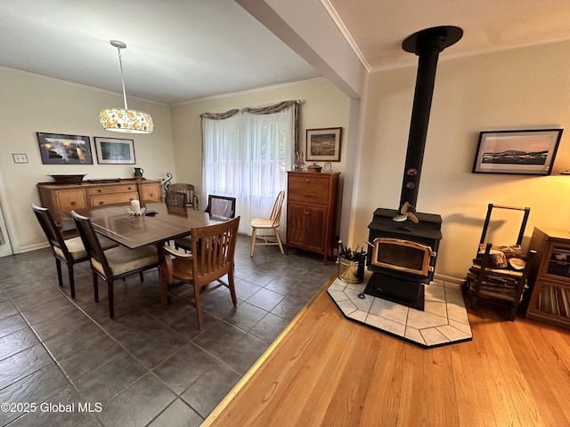 dining room with baseboards, dark wood-type flooring, ornamental molding, and a wood stove