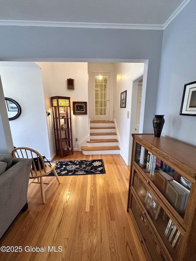 hall featuring light wood finished floors, stairway, crown molding, and baseboards