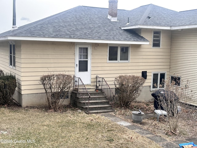 back of property with a chimney and a shingled roof