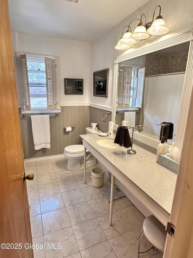 bathroom with a shower with curtain, toilet, wood walls, and wainscoting