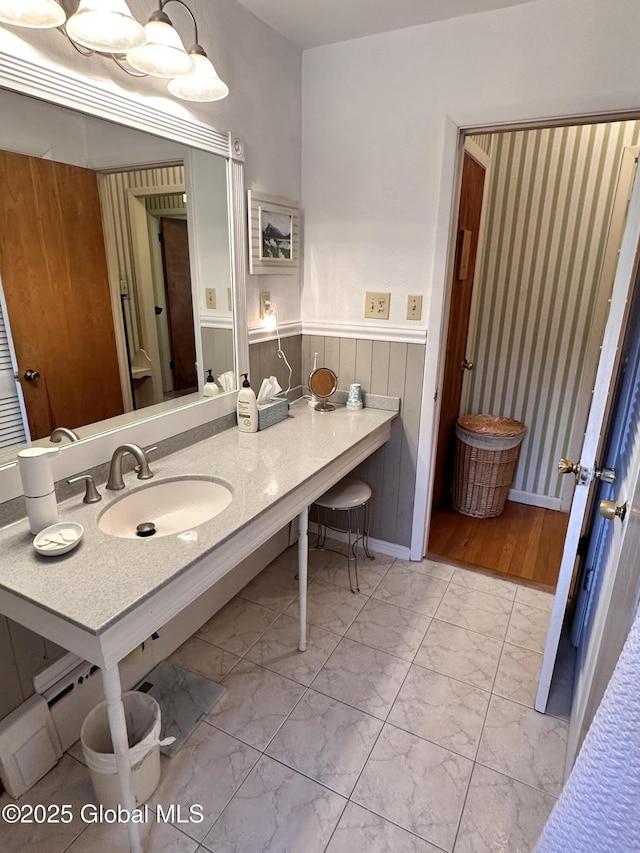 bathroom with a wainscoted wall, marble finish floor, and a sink