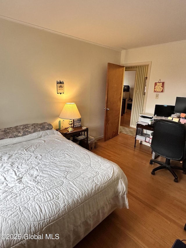 bedroom with crown molding and wood finished floors