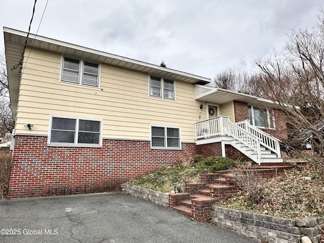 tri-level home with stairway, a patio area, and brick siding