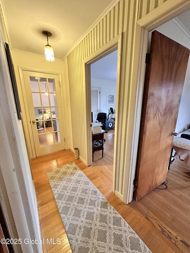 hallway with french doors, wallpapered walls, crown molding, and hardwood / wood-style floors