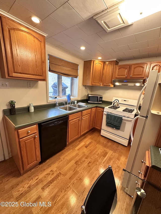 kitchen with under cabinet range hood, light wood-type flooring, brown cabinets, white appliances, and a sink