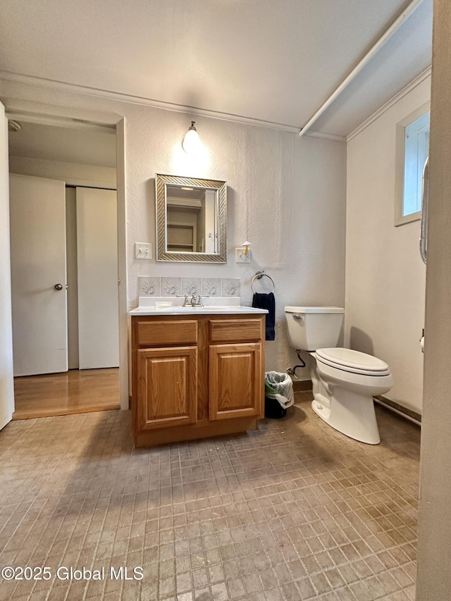 bathroom with toilet, vanity, and crown molding
