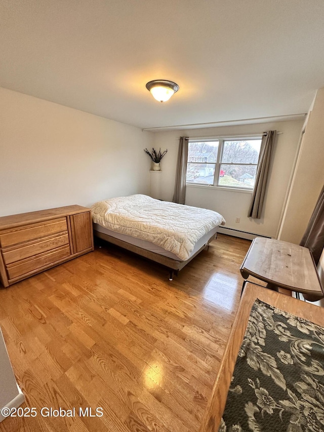 bedroom with a baseboard heating unit and light wood-style floors